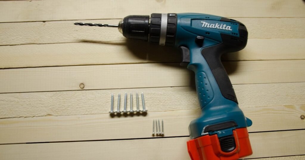 Makita cordless drill with battery pack and screws on a timber surface